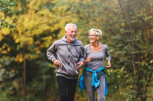 happy senior couple jogging together in autumn park enjoying fitness and healthy lifestyle