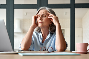woman experiencing stress while working on a laptop in a cozy indoor setting with a cup beside her feeling overwhelmed by thoughts related to 13 challenges of daily life