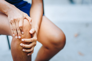 person sitting with hand on knee experiencing discomfort or pain related to joint issues among common injuries in sports activities or daily life 10 essential tips for knee health