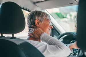senior woman experiencing neck pain while driving in car suggesting need for relief and comfort during 15 minute journey