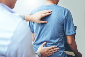 person receiving back treatment with therapists hand on shoulder focused on wellness 14 chiropractic adjustments