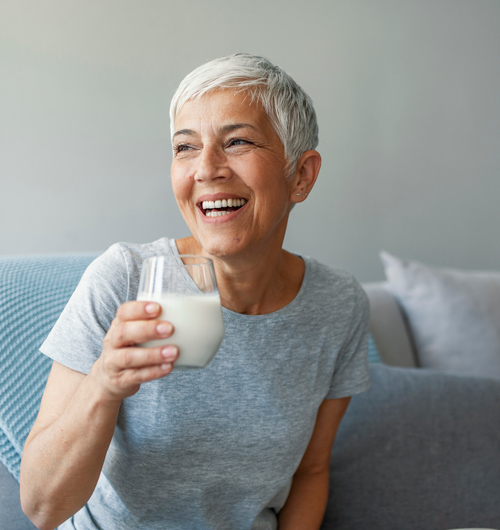 happy senior woman enjoying milk sitting on a couch celebrating health at 14 years young