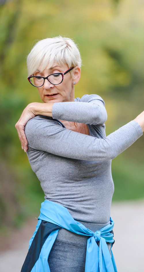 active senior woman stretching arms outdoors in nature enjoying healthy lifestyle exercise routine 2 fitness tips